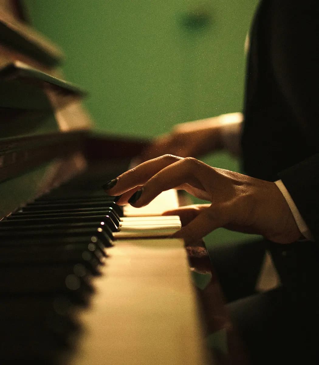 Mani che suonano un pianoforte in penombra.