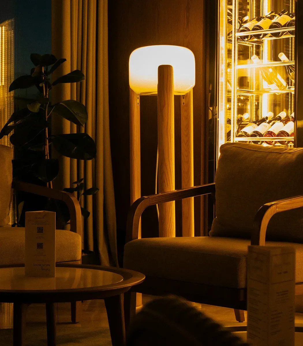 Angolo lounge del locale con poltrone, luce calda e una cantinetta di vini illuminata sullo sfondo.